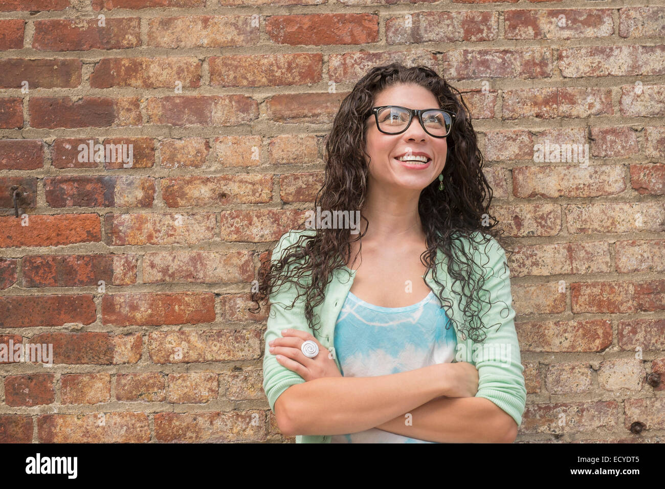 Pensive mixed race woman standing with arms crossed Banque D'Images