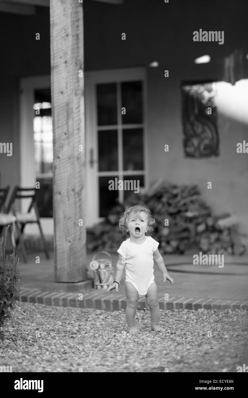 Caucasian baby boy standing on gravel in backyard Banque D'Images