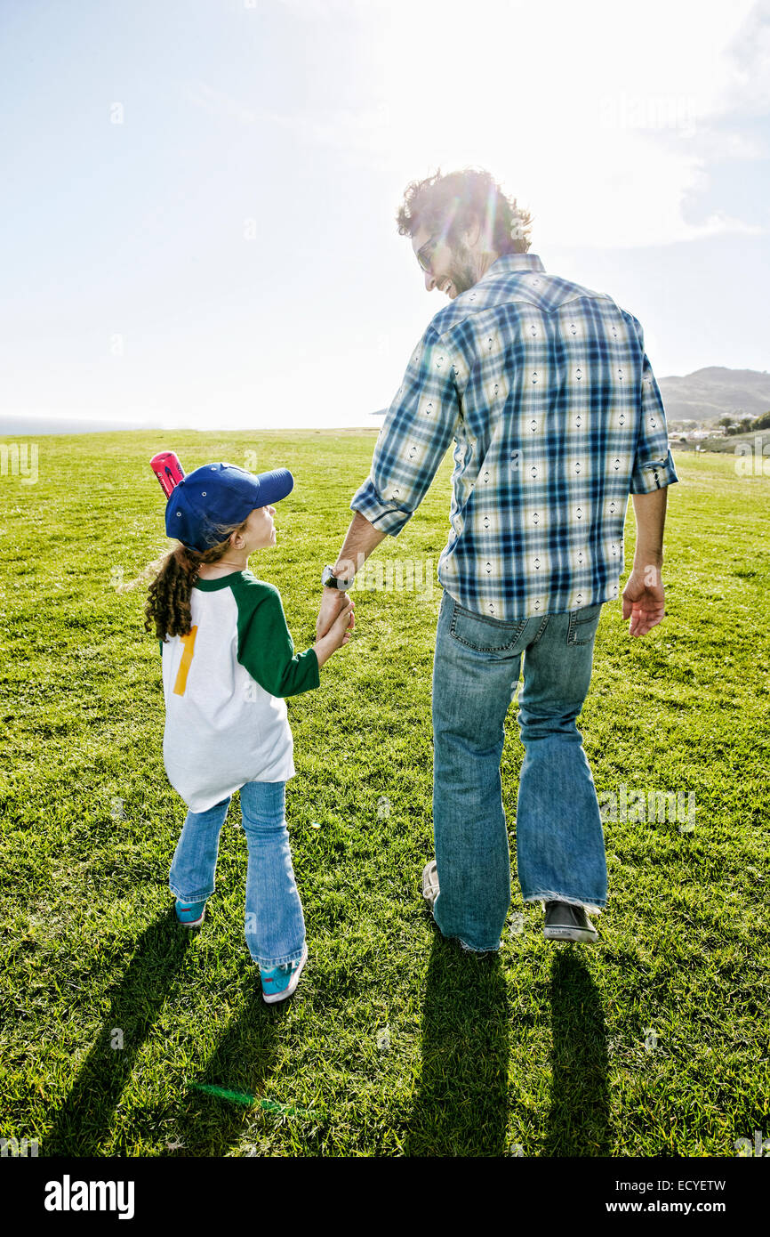 Père et fille walking in grassy field Banque D'Images