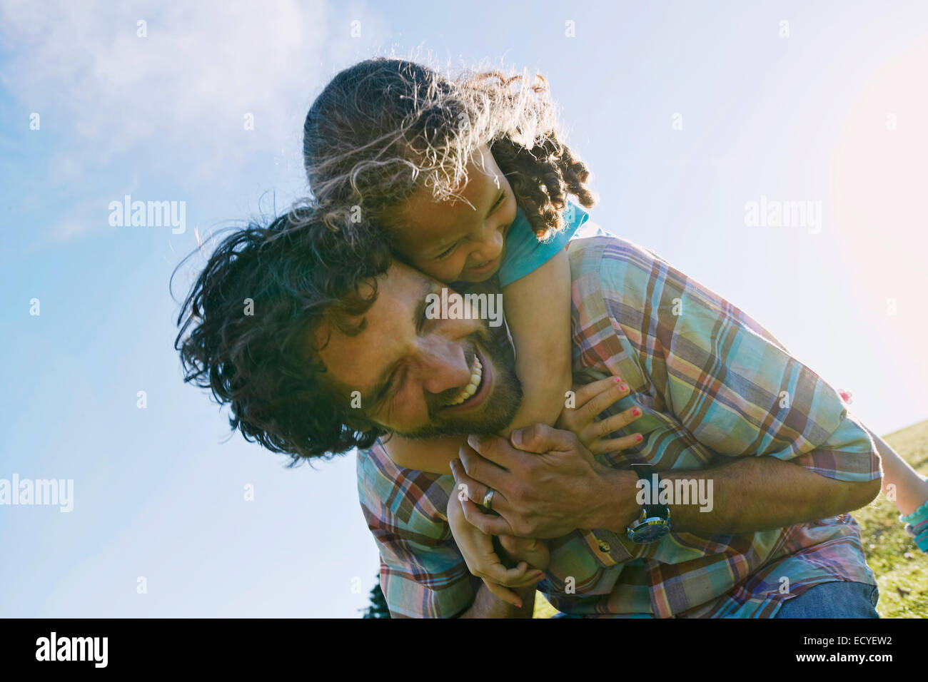 Low angle view of father carrying daughter piggyback outdoors Banque D'Images