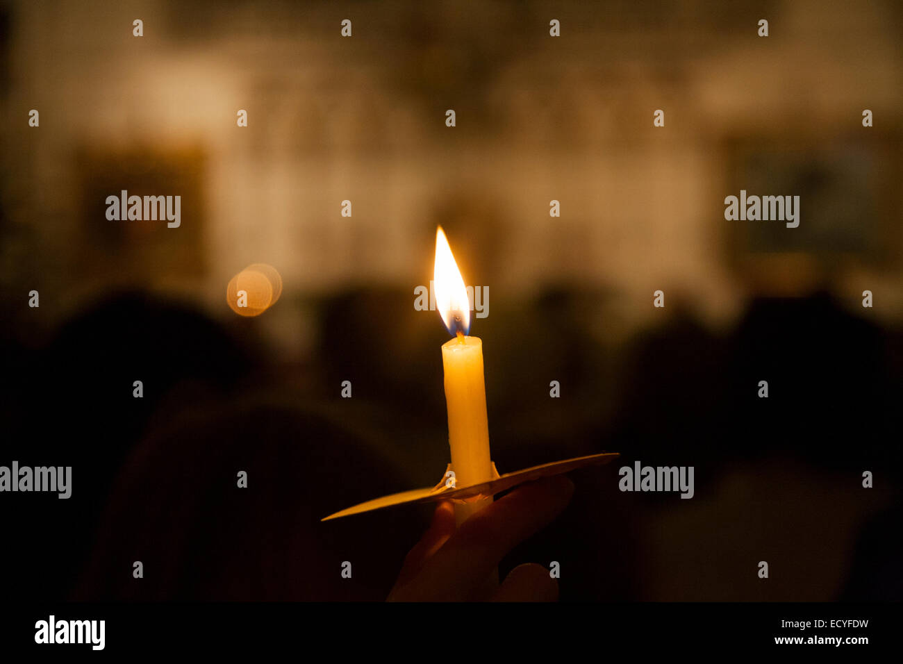 L'une 1 seule bougie flamme lumière solitaire au cours d'une Église chrétienne éclairée aux chandelles / Masse service carol & congrégation paroissiens UK Banque D'Images