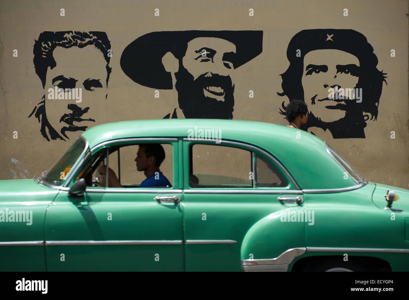 La HAVANE, CUBA - le 13 juin 2011 : les lecteurs de voiture américaine classique passé avec panneau pochoir Mella, Cienfuego, et Guevara. Banque D'Images