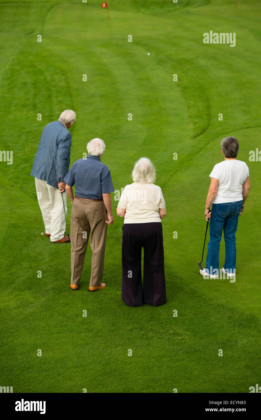 Un groupe de 4 personnes âgées, quatre couples retraités, les retraités en vacances locations playing miniature golf, UK Banque D'Images