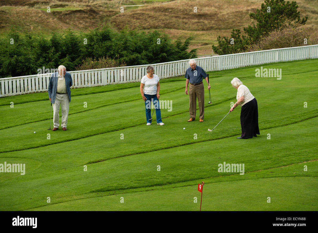 Un groupe de 4 personnes âgées, quatre couples retraités, les retraités en vacances locations playing miniature golf, UK Banque D'Images