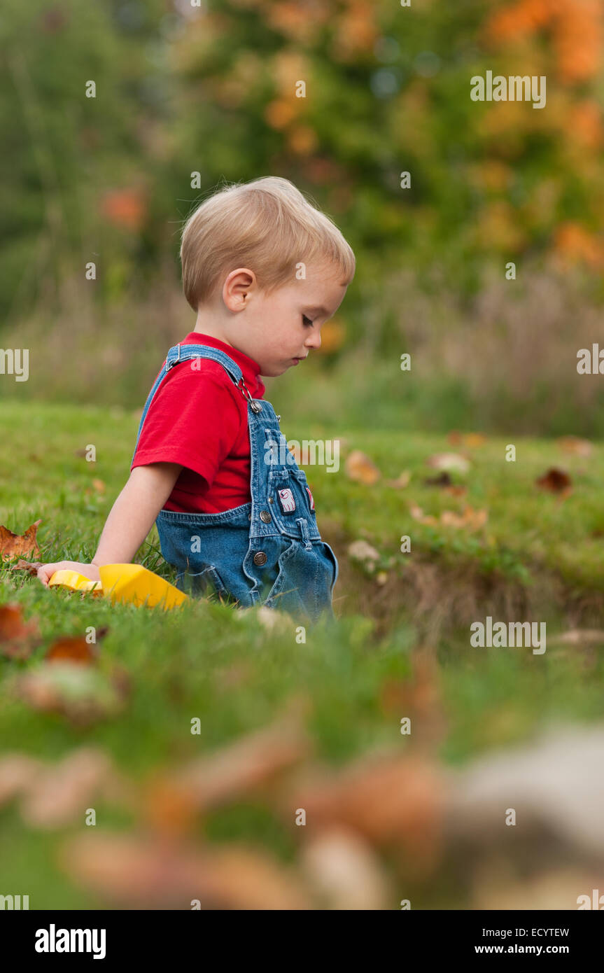 Profil d'un deux-année-vieux garçon en denim bleu de travail à l'automne. Banque D'Images