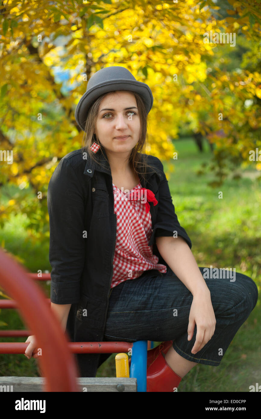 Teenage girl (16-17) avec hat relaxing on playground Banque D'Images