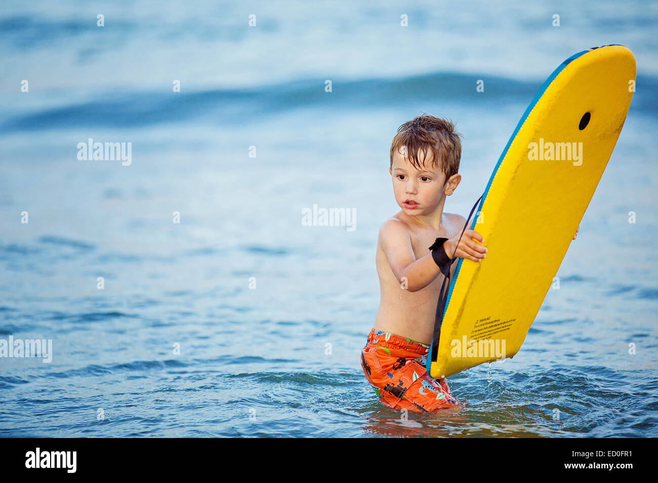 Garçon debout dans la mer avec une petite planche de surf Photo Stock -  Alamy