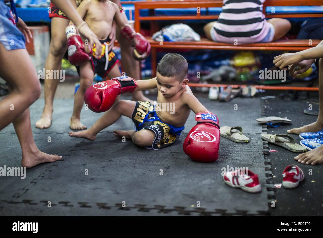 Bangkok, Bangkok, Thaïlande. Dec 23, 2014. Un garçon atterrit sur le plancher après l'entraînement dans la salle de sport Kanisorn à Bangkok. Le Kanisorn boxing gym est une petite salle de sport le long de la Wong Wian Yai - Samut Sakhon voie ferrée. Les jeunes des communautés voisines viennent à la salle de sport pour apprendre la boxe. Le Muay Thai (Muai thaï) est un art martial mixte développé en Thaïlande. Le Muay Thai est devenue très répandue dans le monde au xxe siècle, quand les boxeurs Thaï défait d'autres boxeurs bien connu. Une ligue professionnelle est régie par le monde Conseil de Muay Thai. Muay Thai est souvent considérée comme un moyen de sortir de la pauvreté pour Banque D'Images
