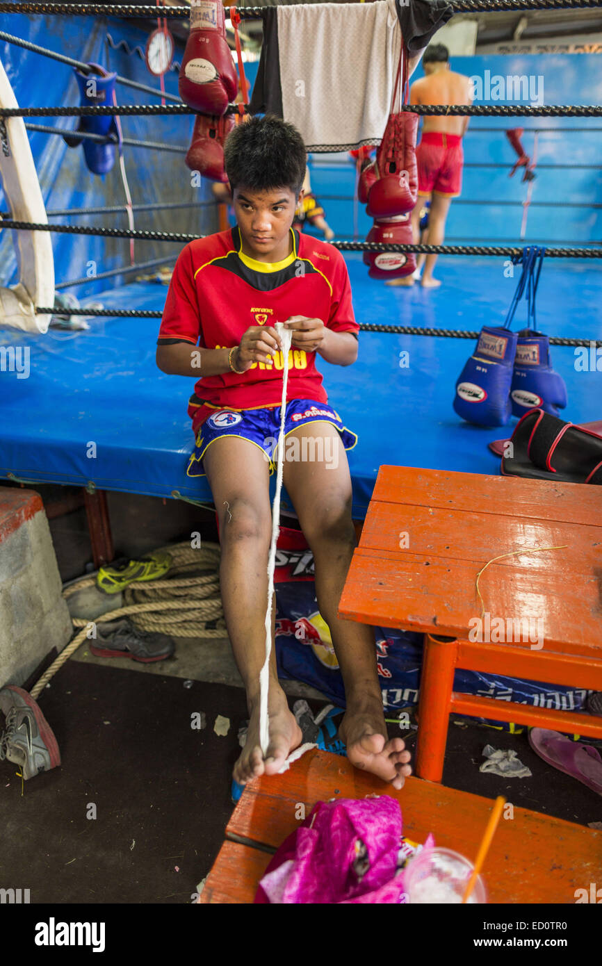 Bangkok, Bangkok, Thaïlande. Dec 23, 2014. Un boxeur se déroule une bande pour ses mains avant de l'entraînement à la salle de sport Kanisorn à Bangkok. Le Kanisorn boxing gym est une petite salle de sport le long de la Wong Wian Yai - Samut Sakhon voie ferrée. Les jeunes des communautés voisines viennent à la salle de sport pour apprendre la boxe. Le Muay Thai (Muai thaï) est un art martial mixte développé en Thaïlande. Le Muay Thai est devenue très répandue dans le monde au xxe siècle, quand les boxeurs Thaï défait d'autres boxeurs bien connu. Une ligue professionnelle est régie par le monde Conseil de Muay Thai. Muay Thai est souvent considérée comme un moyen de p Banque D'Images