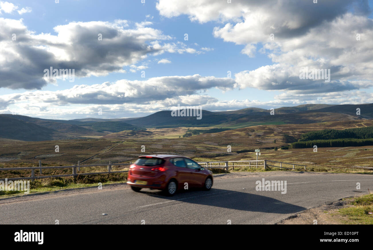 Une voiture sur l'A938 entre Corgarff et Garnshiel avec pont les collines et de grouse landes du Parc National de Cairngorms derrière Banque D'Images