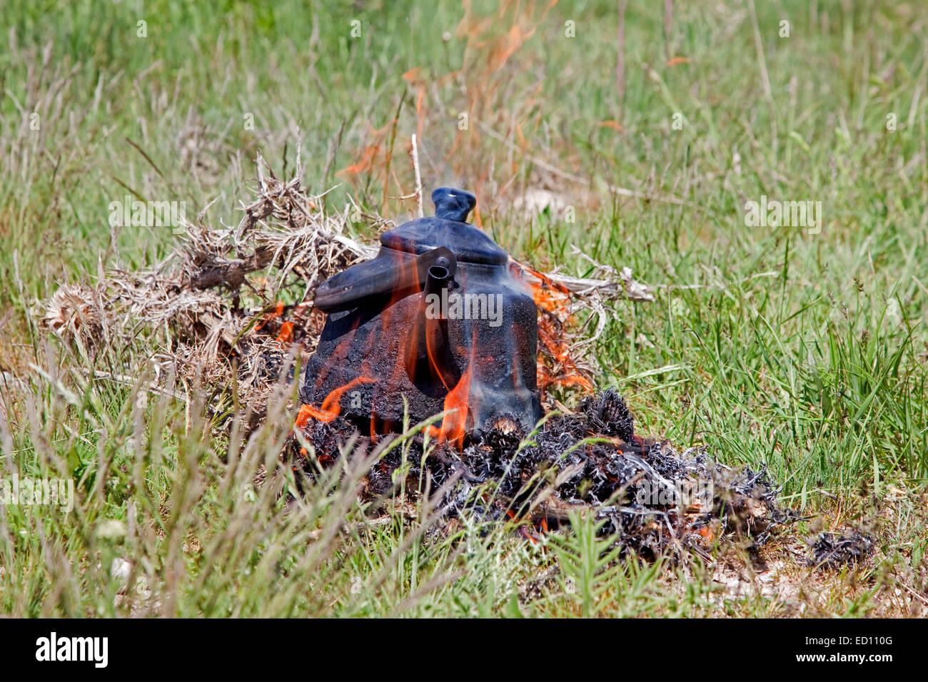 Une eau bouillante noircie électrique dans les flammes d'un feu de camp pour faire du thé Banque D'Images