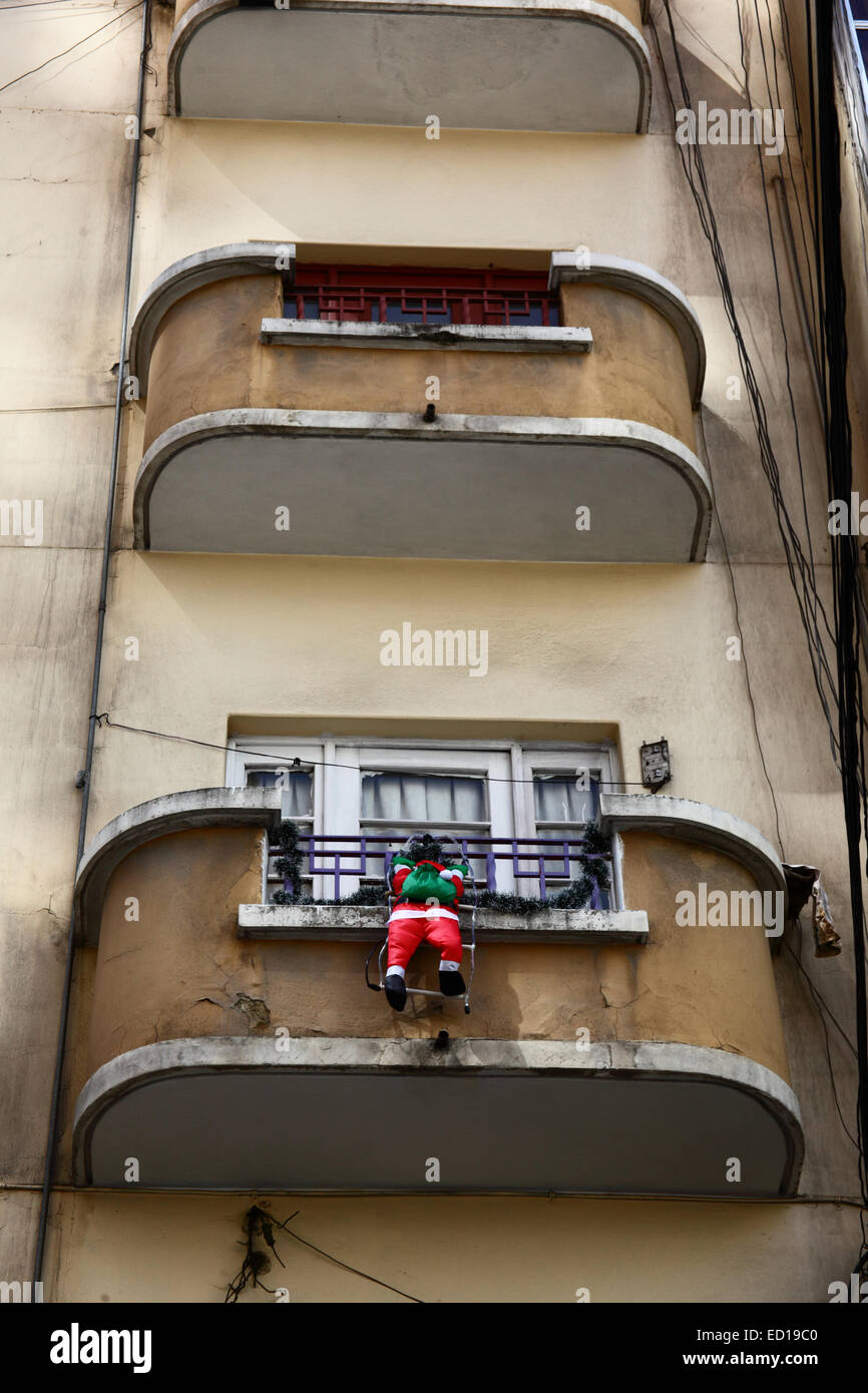 La Paz, Bolivie. Dec 23, 2014. La figure d'un Père Noël gonflable suspendu à un balcon tout en grimpant sur un immeuble de plusieurs étages dans le centre-ville. Credit : James Brunker / Alamy Live News Banque D'Images