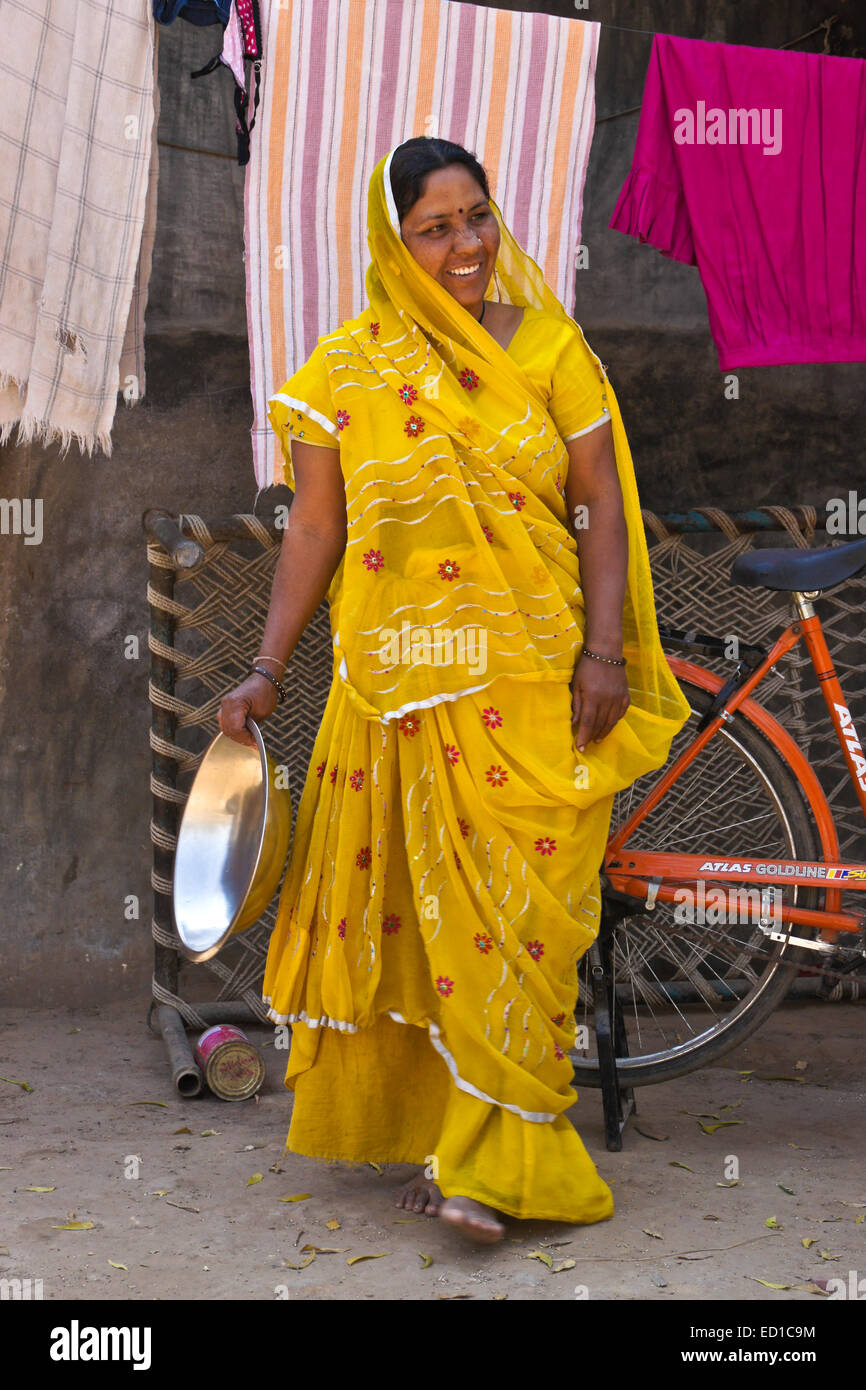 Femme en costume traditionnel étendre le linge à l'extérieur de sa maison, Modhera, Gujarat, Inde Banque D'Images