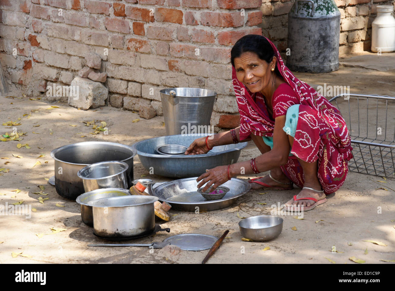 Femme en costume traditionnel pots nettoyage devant sa maison, Modhera, Gujarat, Inde Banque D'Images