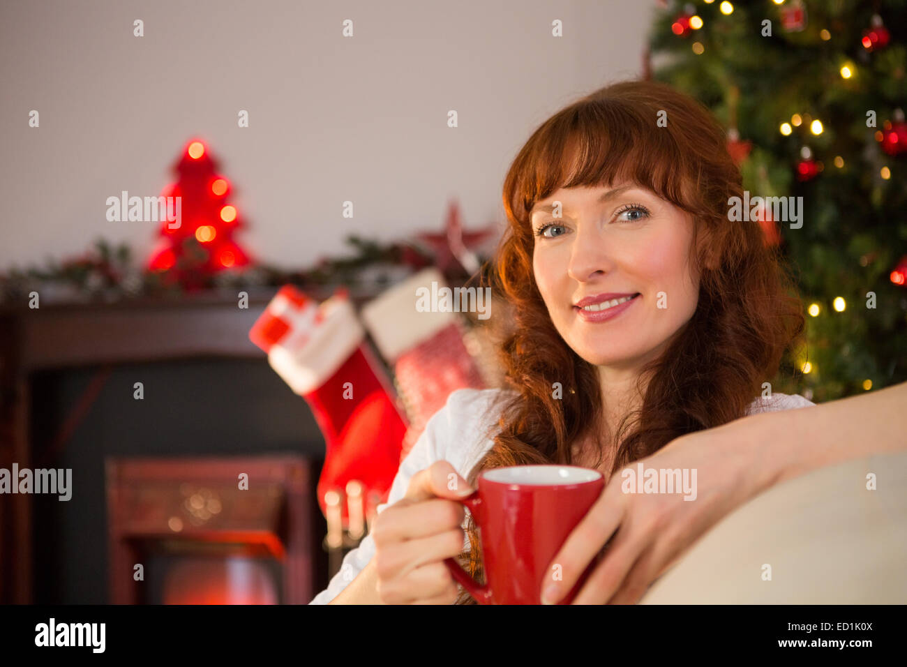 Smiling redhead tenant une tasse de boisson chaude à Noël Banque D'Images
