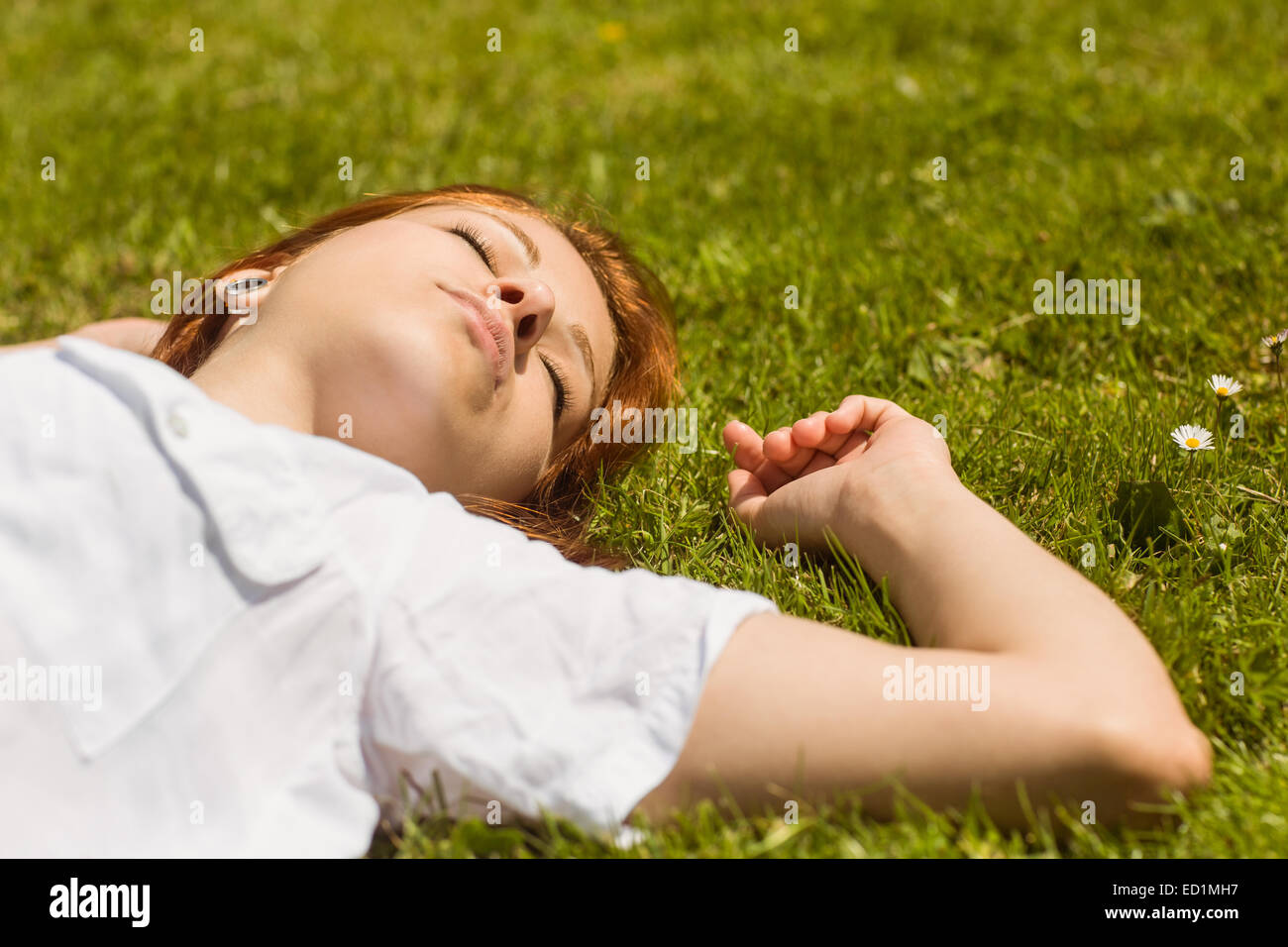 Jolie rousse la sieste sur l'herbe Banque D'Images
