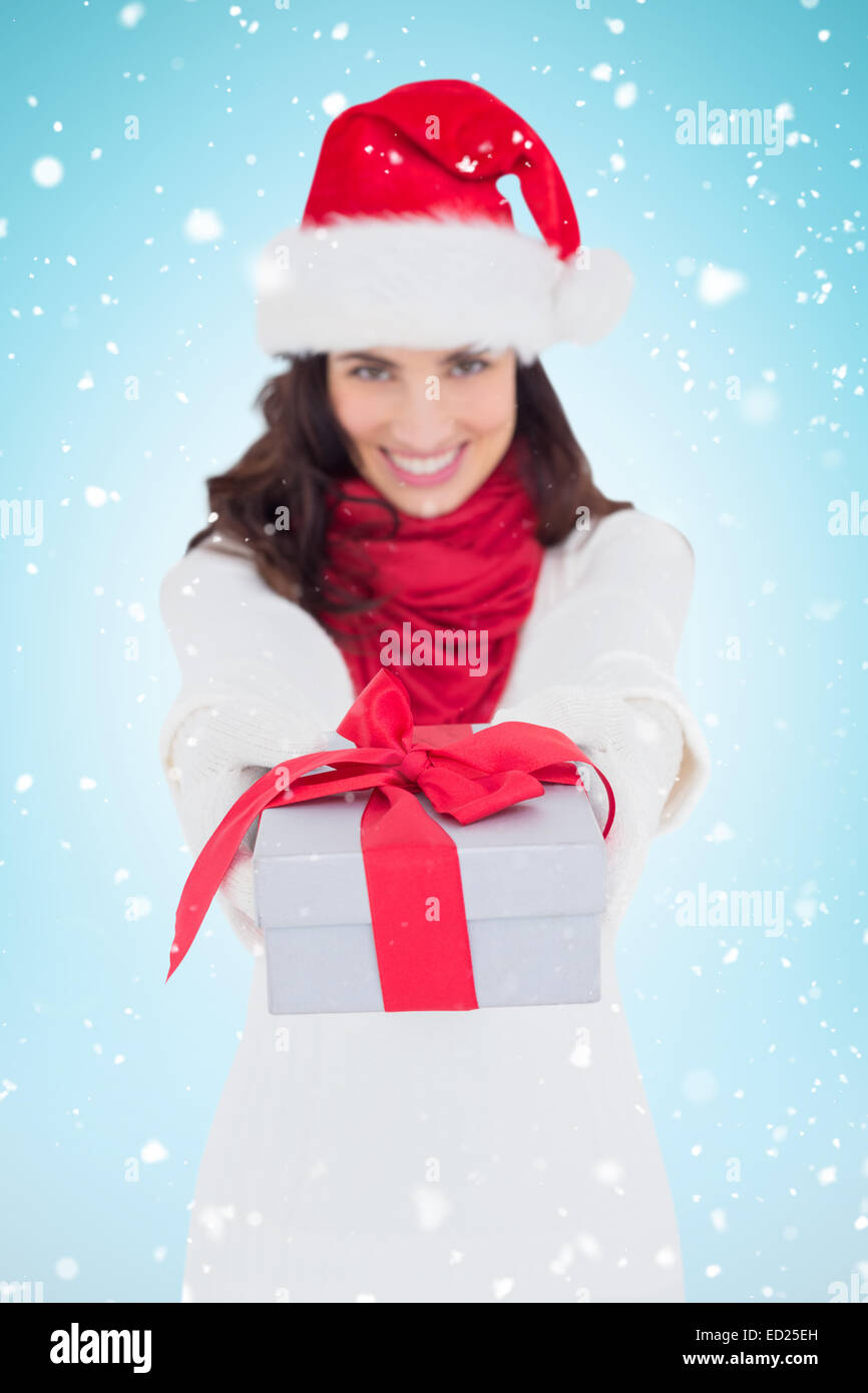 Image composite de brunette de fête à santa hat giving gift Banque D'Images