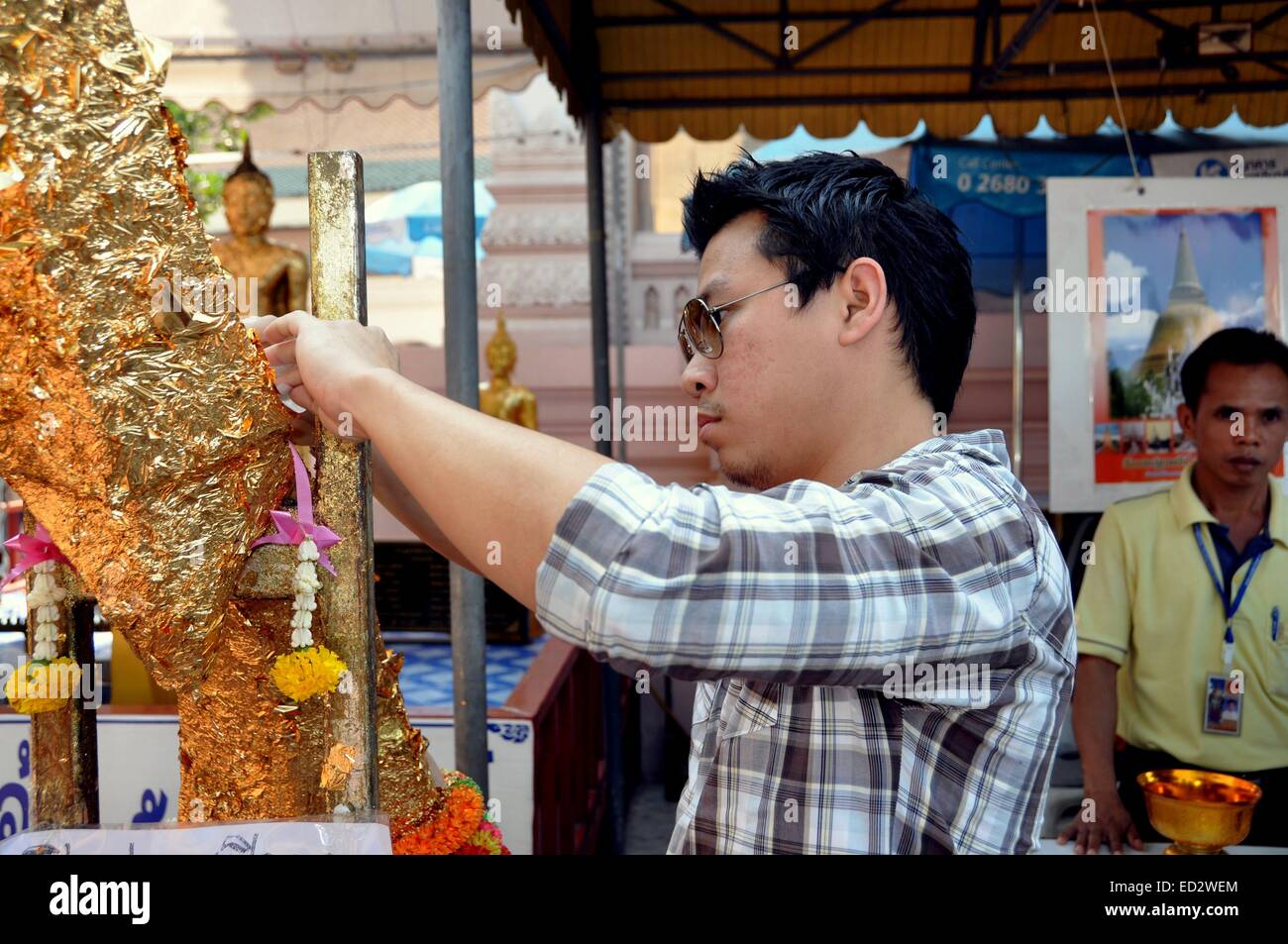 NAKHON PATHOM, THAÏLANDE : Jeune homme applique un morceau de feuille d'or l'appliqué à la figure d'un Bouddha Banque D'Images