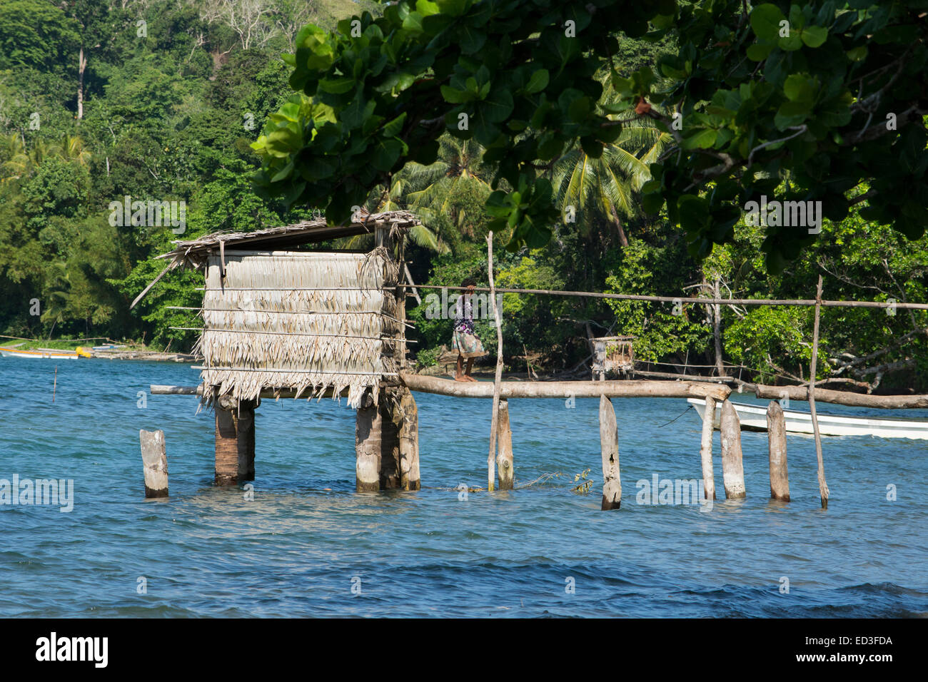 En Mélanésie, la Papouasie-Nouvelle-Guinée, l'île de Dobu. Village typique de l'île au fil de l'eau outhouse, jeune fille dans le passage libre. Banque D'Images