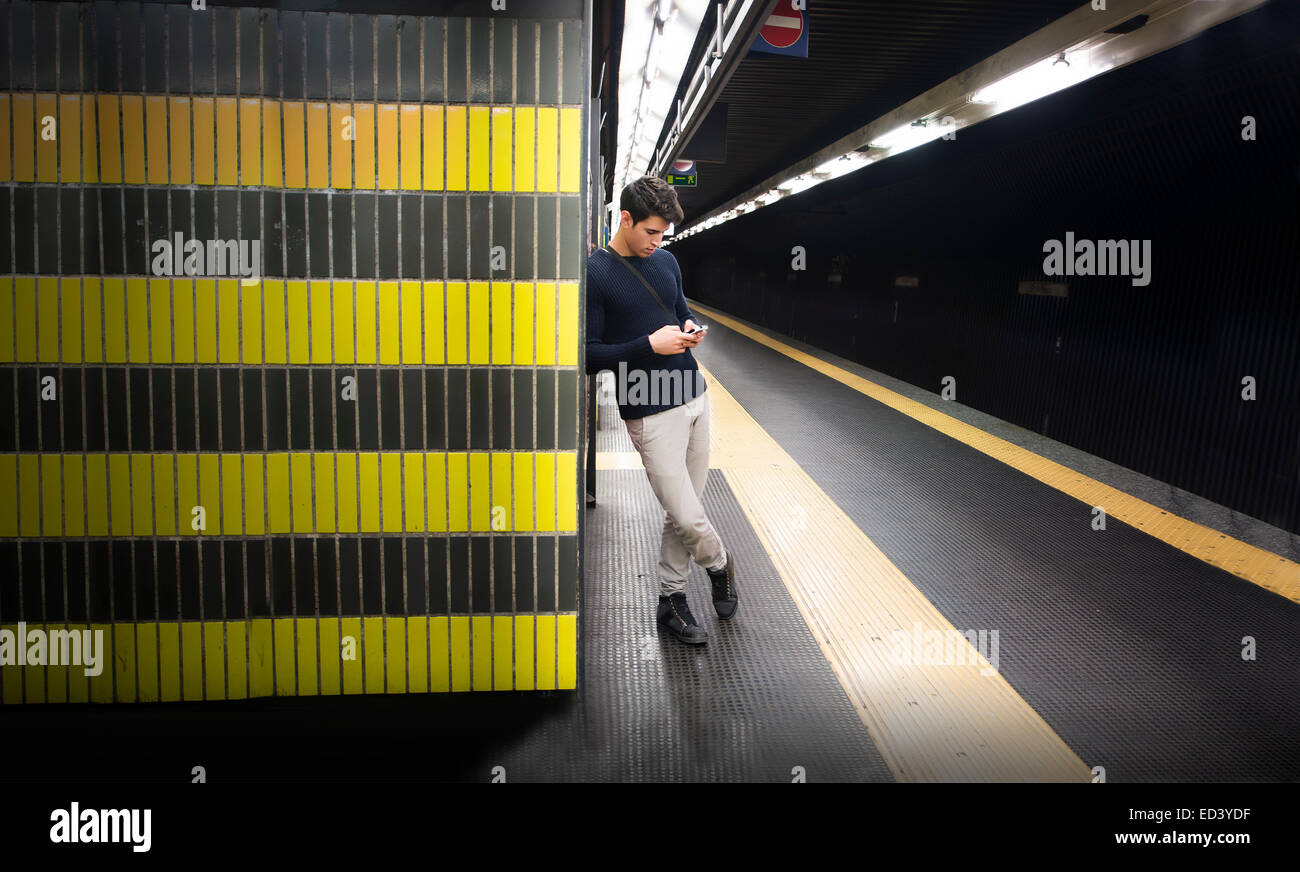 Jeune homme attrayant dans la station de métro ou de train à l'aide de téléphone mobile (mobile) Banque D'Images