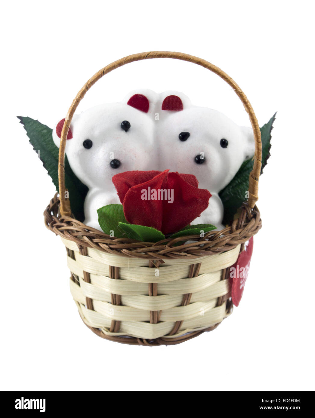 Un mignon petit ours en peluche blanc avec avec rose dans le panier. Banque D'Images
