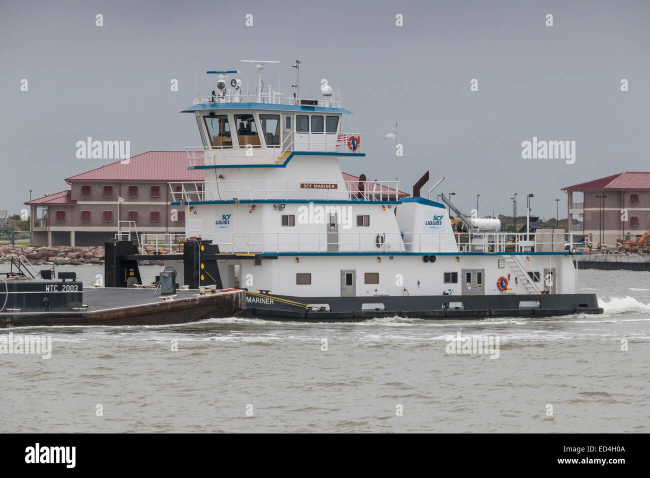 Barge et remorqueur de Galveston chenal du port en passant en face de la station de la Garde côtière canadienne. Banque D'Images