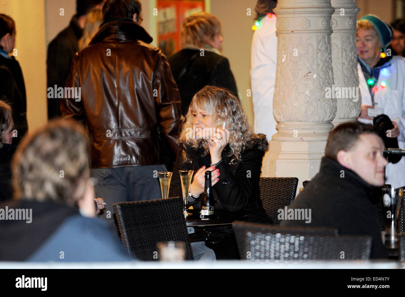 Brighton UK - Femme assise à la terrasse d'un bar tableau fumer une cigarette avec un verre de vin mousseux Banque D'Images