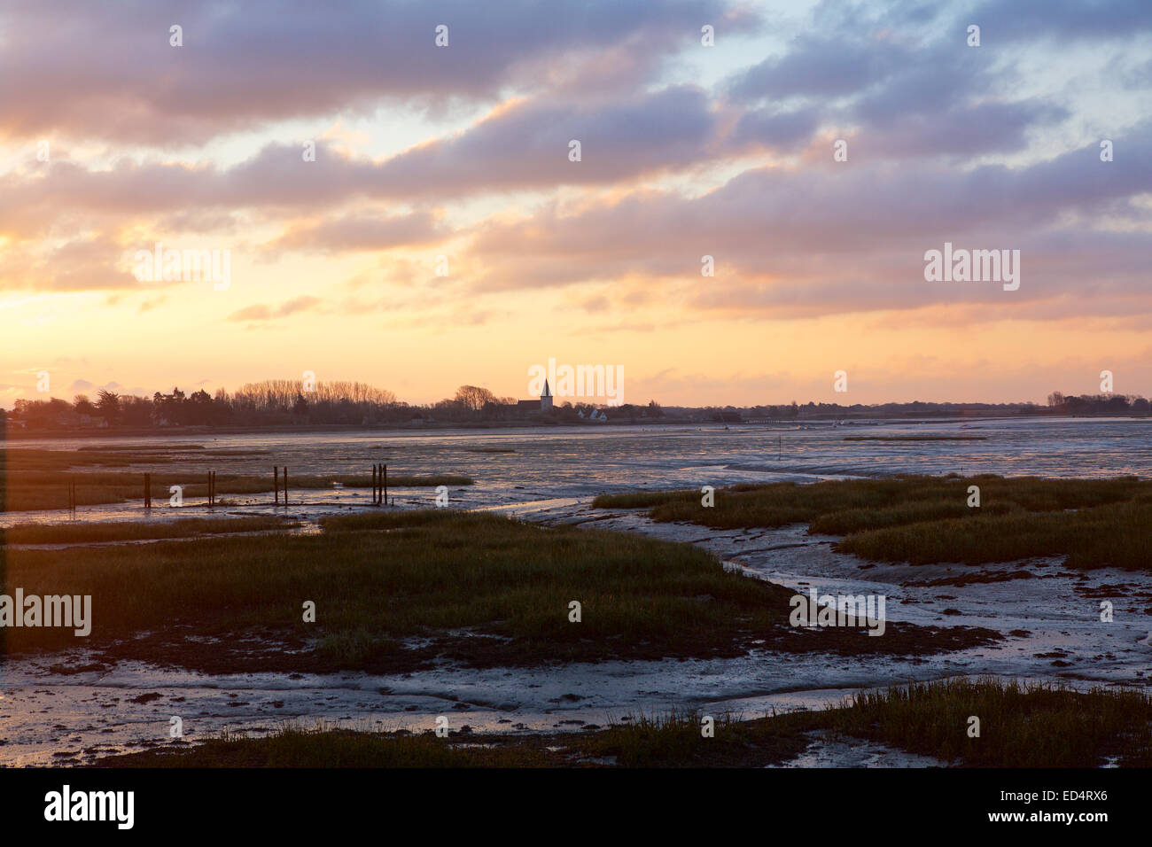 Chichester Harbour Sunrise. Lever de soleil coloré se brisant au-dessus du village de Bosham à marée basse. Brillent sur les marais et la boue qui entourent la région. Banque D'Images