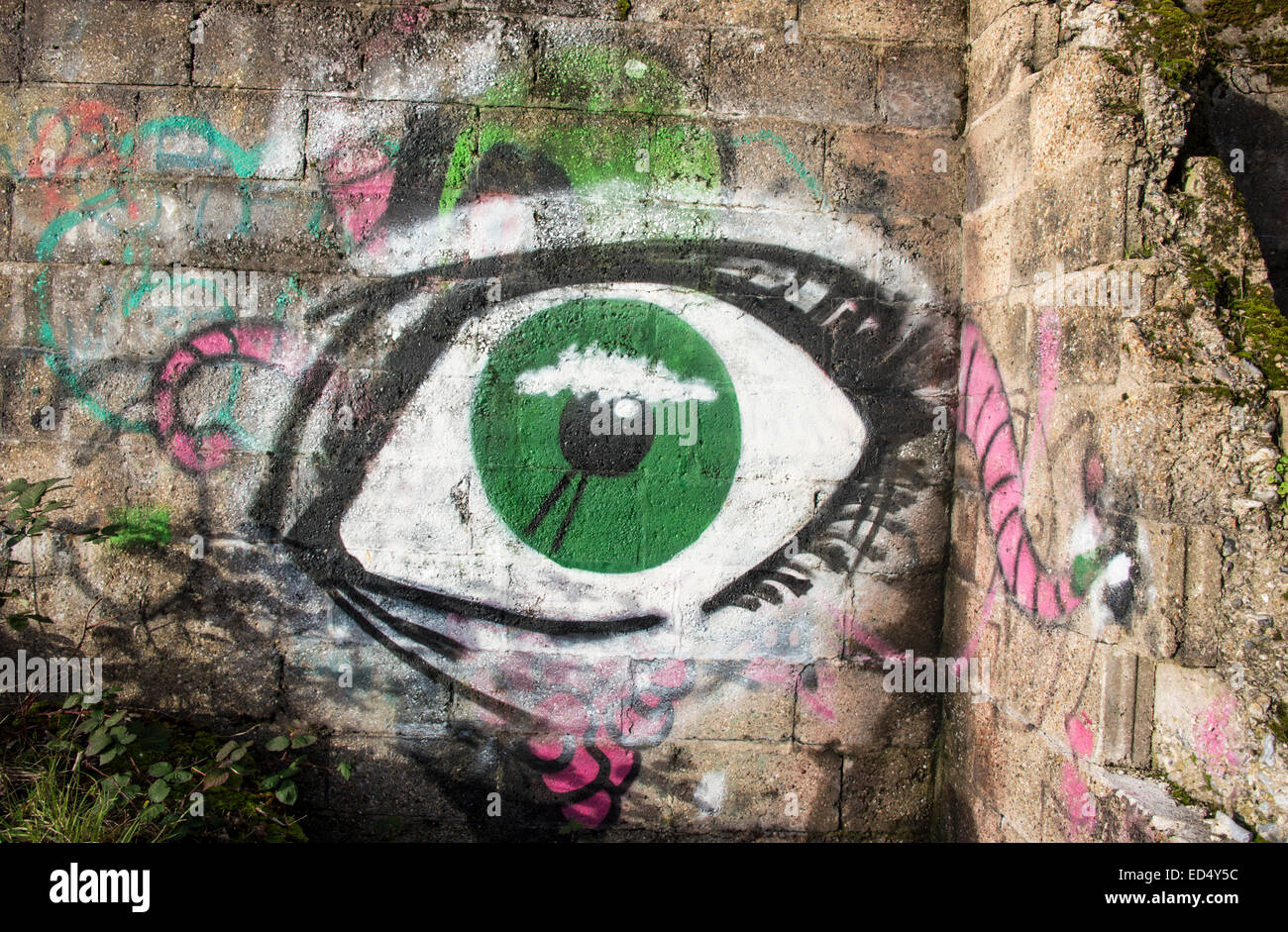 Graffiti dans la forme d'un œil vert sur les ruines d'une structure défensive WW2 Banque D'Images