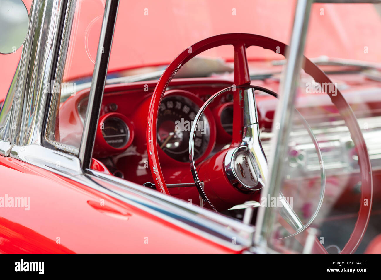 À l'intérieur d'une voiture américaine classique vintage rouge prises lors d'un rassemblement. Montrant le volant et tableau de bord d'horloges. Banque D'Images