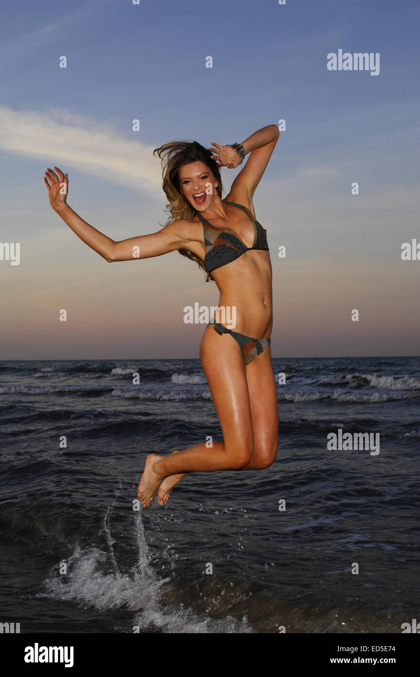 Femme en costume de bain sautant sur beach Banque D'Images