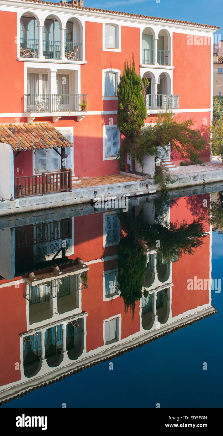 Un petit rouge bâtiment typique de Port Grimaud, dans le sud de la France, se reflète dans l'eau calme d'un canal Banque D'Images