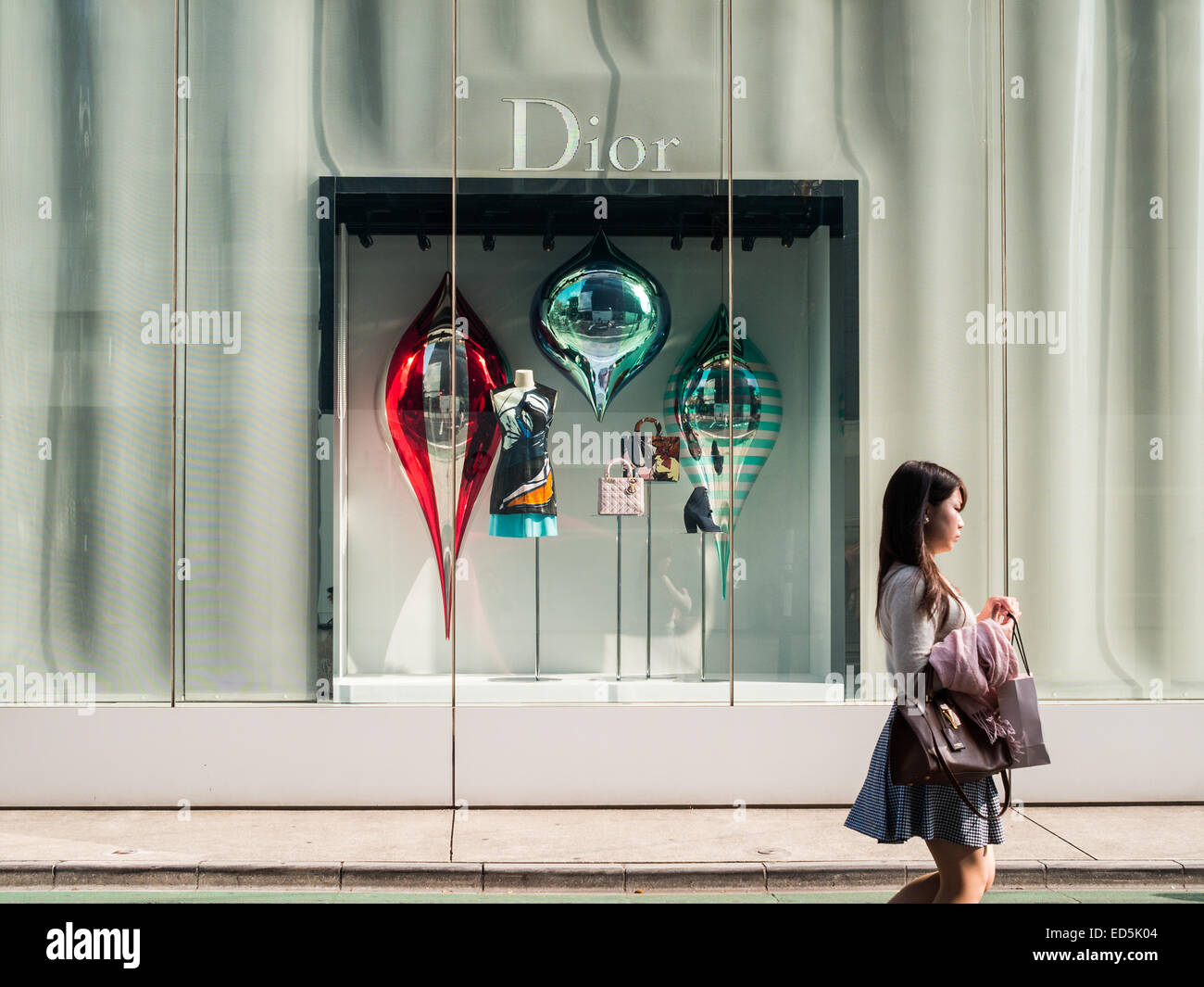 Femme passant par la fenêtre du magasin Dior dans la rue Omotesando Banque D'Images