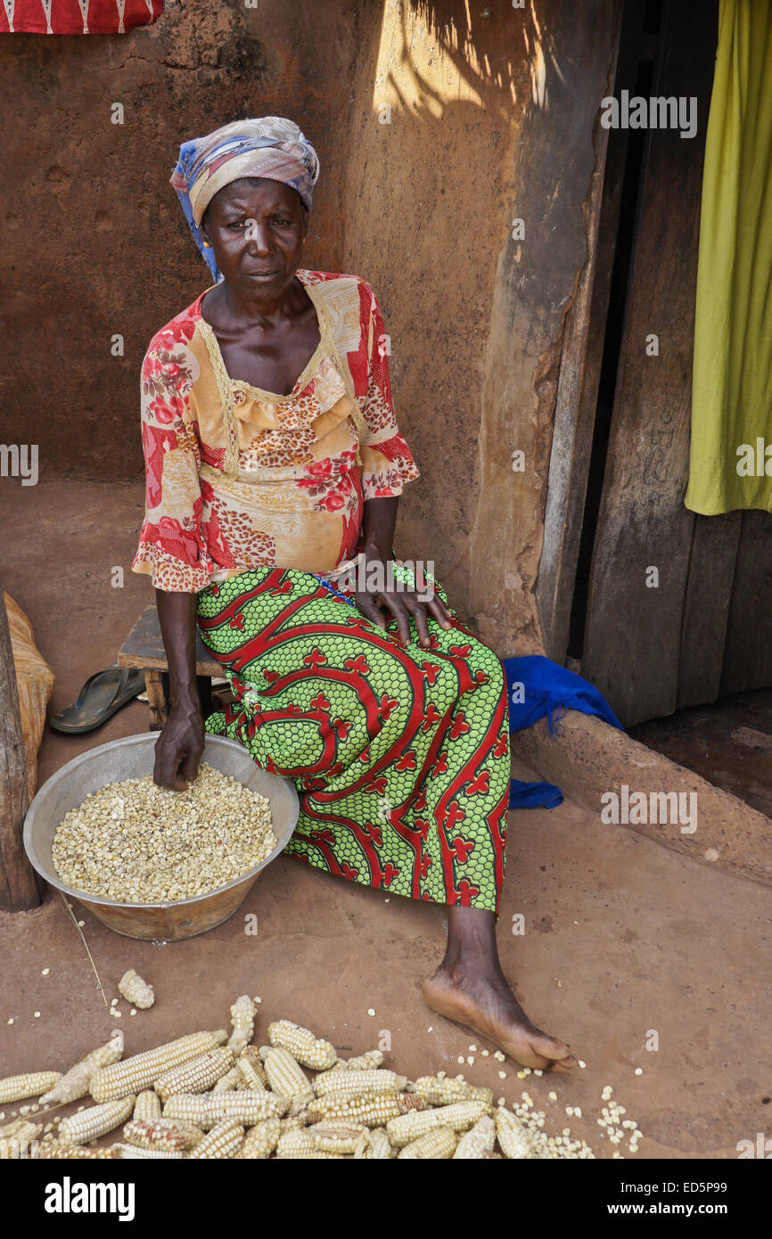 Des épis de maïs femme dépose devant sa cabane de torchis, Gambaga, Ghana Banque D'Images