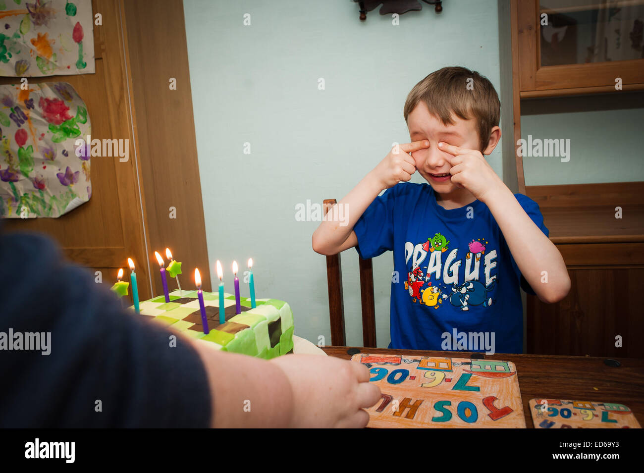 Garçon fermer les yeux pour le gâteau d'anniversaire surprise Banque D'Images