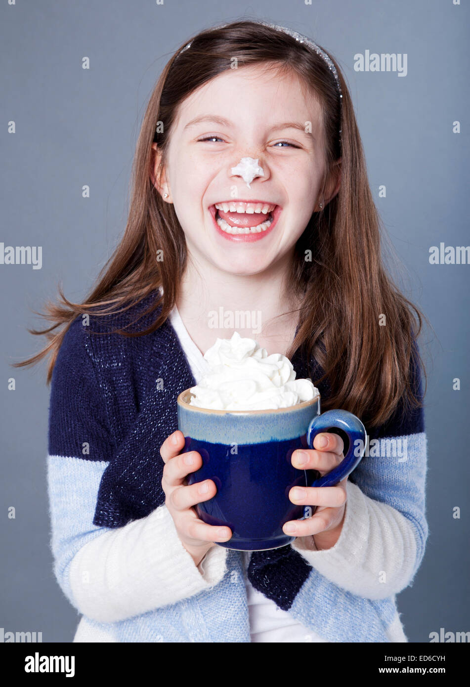 Petite fille hystérique avec une tasse de chocolat chaud et crème fouettée sur son nez Banque D'Images