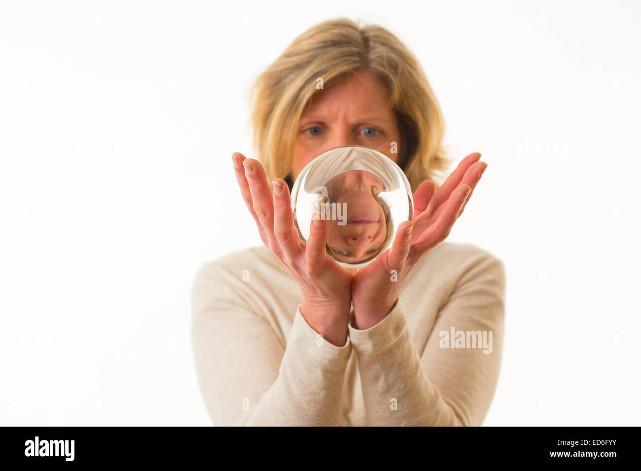 Regard sur l'avenir : un adulte âgé de 40 ans à la femme de race blanche à son avenir en regardant dans une boule de cristal qui s'est tenue dans ses mains sur un fond blanc. UK Banque D'Images