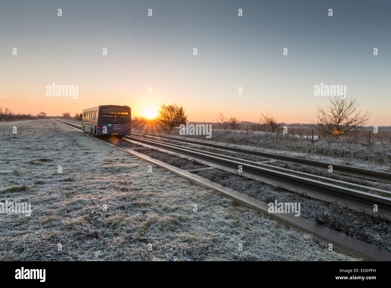 Longstanton près de Cambridge, Royaume-Uni. 30 Décembre, 2014. Météo britannique. Un bus guidé tous les navetteurs à et à partir de la Cambridge sur un gel mais crisp matin au lever du soleil. La température a chuté à moins 1 degrés Celsius la nuit avec un ciel clair, ce qui porte une belle crisp l'aube. Le bus est le plus long du monde dans sa catégorie et s'exécute entre St Ives et Cambridge. Julian crédit Eales/Alamy Live News Banque D'Images