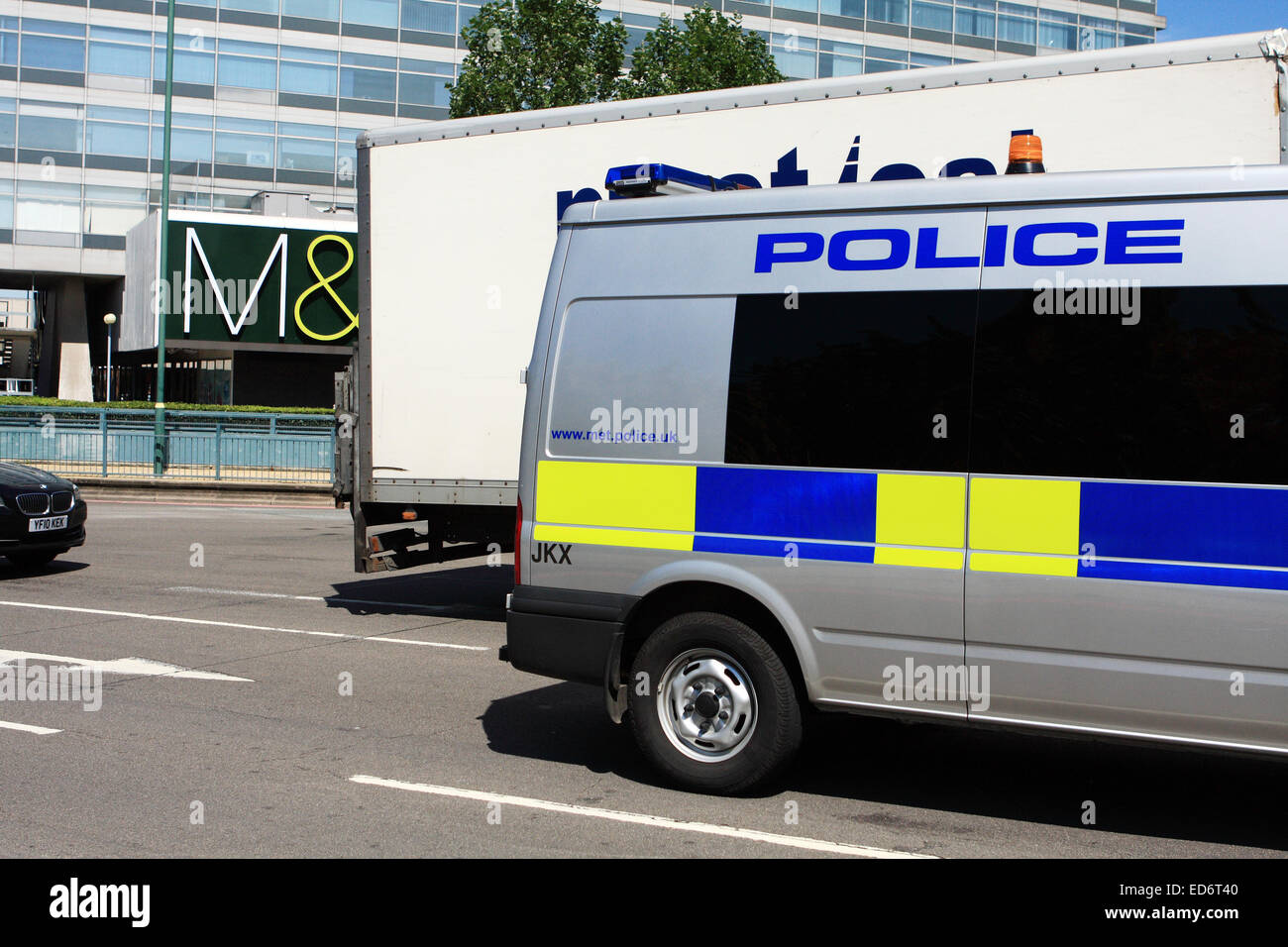 Une partie de l'arrière d'un fourgon de police et d'autres véhicules circulant autour d'un rond-point à Tolworth, Surrey, Angleterre. Banque D'Images