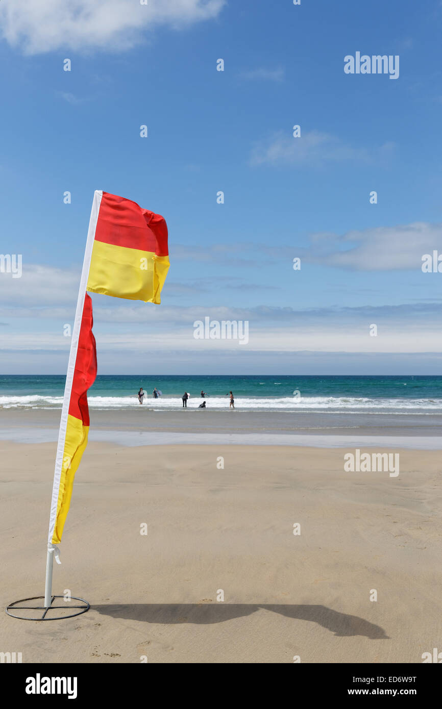 Drapeau jaune et rouge de la vie des gardiens pour marquer l'économiser une partie de la plage de fistral par un jour de vent à Newquay, Cornwall, UK. Banque D'Images
