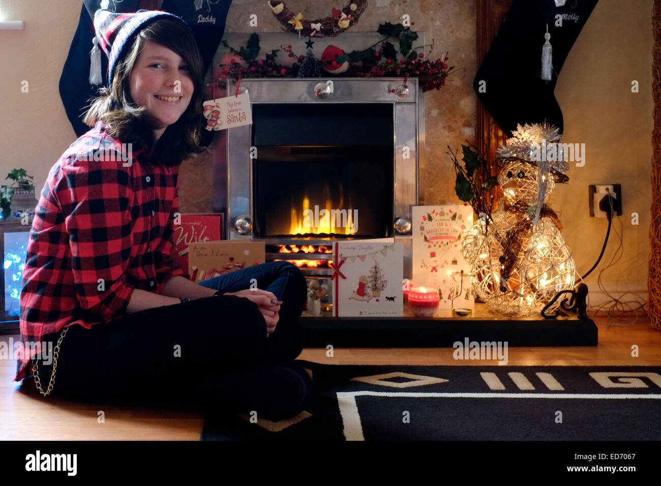 Douze ans smiling girl sitting in front of cheminée décorative à Noël Banque D'Images