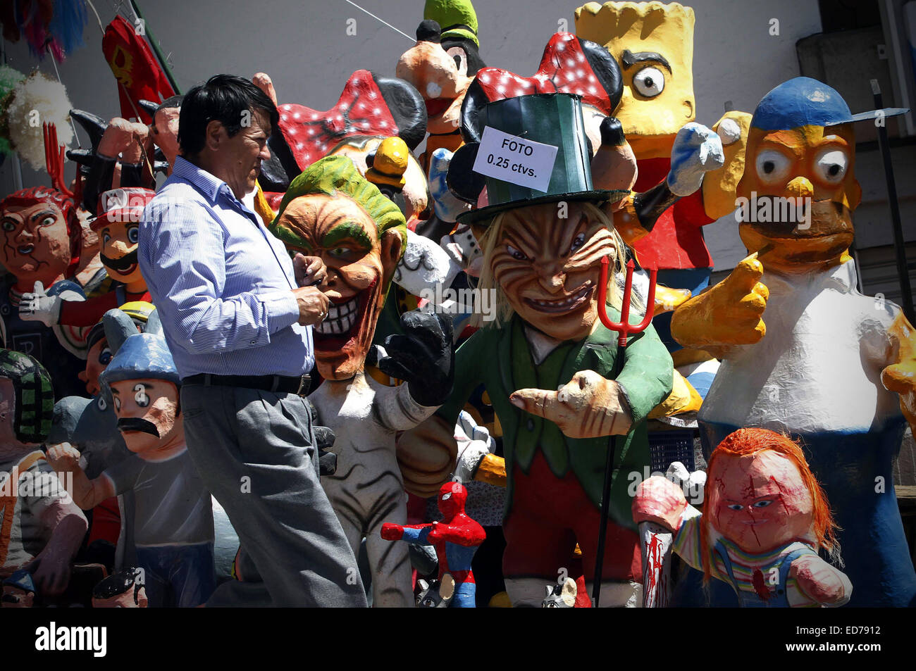 Quito, Equateur. Dec 30, 2014. Un homme marche en avant des figures de film et télévision caractères affichés à vendre dans la ville de Quito, Équateur, le 30 décembre 2014. Les chiffres réalisés en carton sera mis le feu dans le cadre de la tradition locale pour 'brûler' la vieille année de manière à laisser derrière l'expérience négative de l'année dernière et bienvenue la nouvelle année. © Santiago Armas/Xinhua/Alamy Live News Banque D'Images