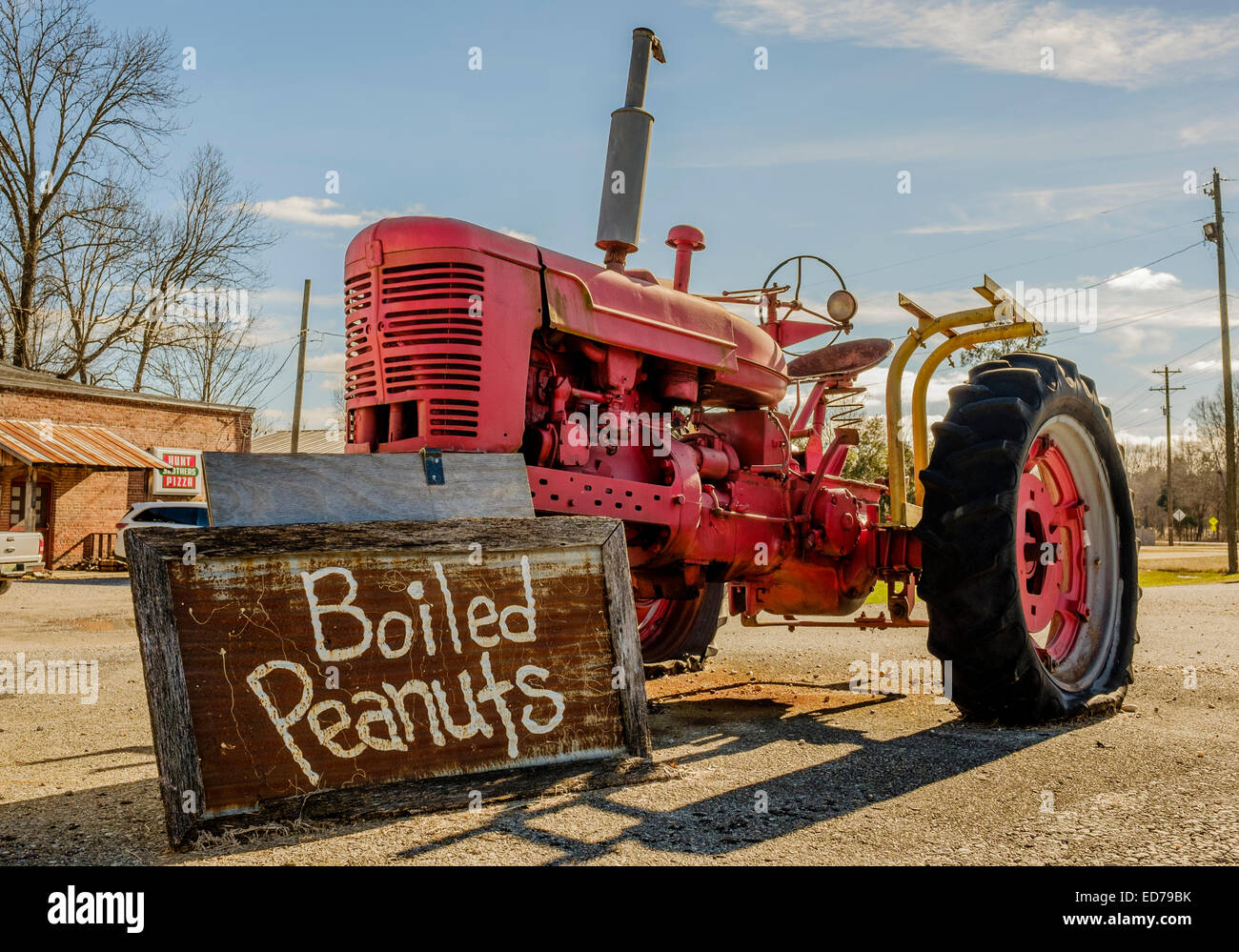 Un vieux tracteur agricole rouge tenant une pancarte dans les arachides bouillies vente Cecil, Alabama, USA. Souvent dans le sud. Banque D'Images