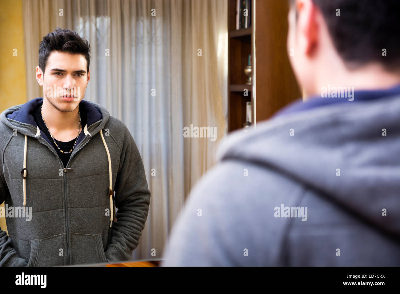 Beau jeune homme, en se regardant dans le miroir à la maison Banque D'Images