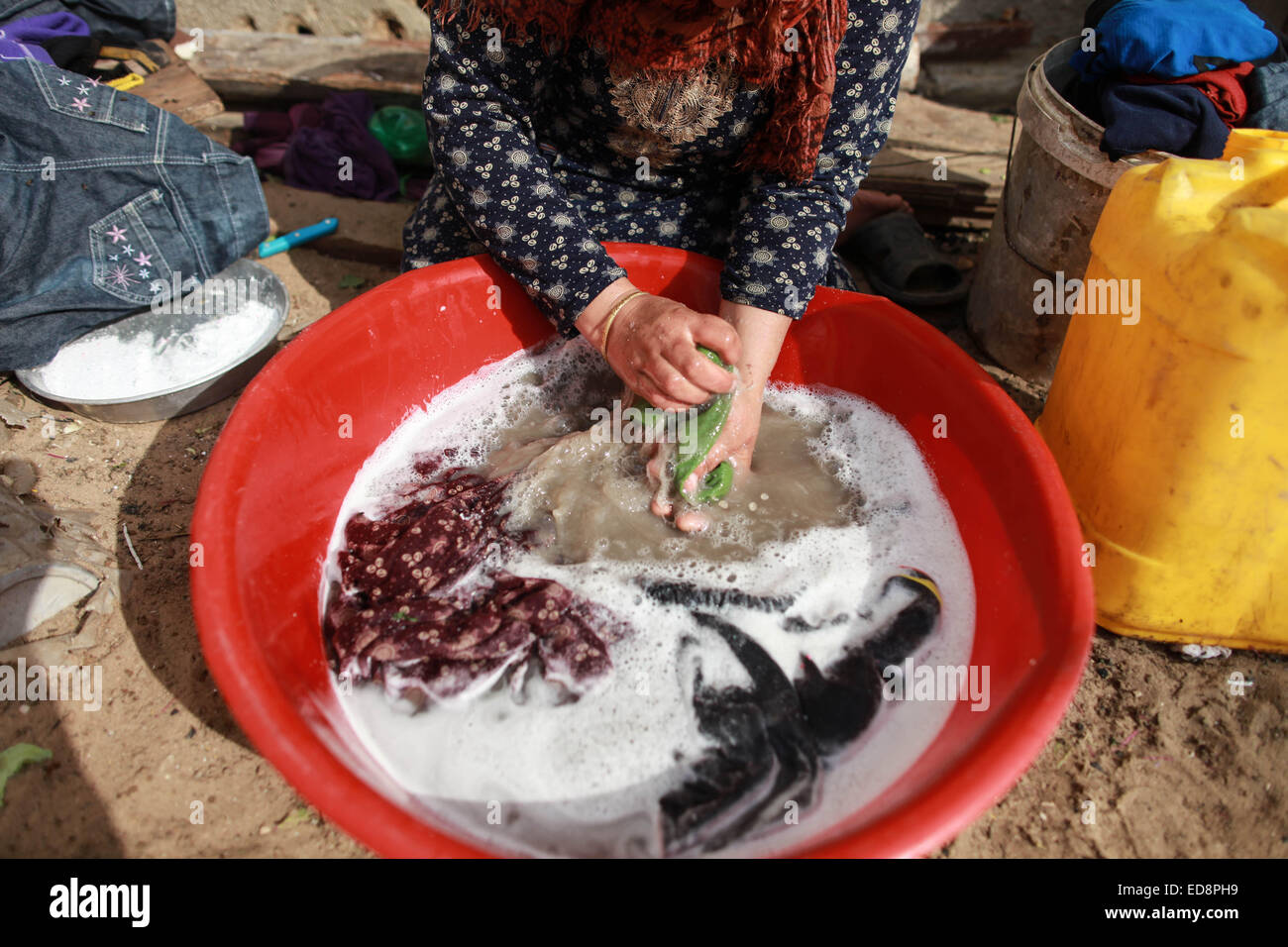 La bande de Gaza. 1er janvier 2015. Une femme se lave les vêtements en face de sa maison dans un quartier pauvre du nord de la bande de Gaza ville de Beit Lahiya au 1er janvier 2015. Les statistiques récentes de la Fédération générale palestinienne des syndicats (PGFTU) ont révélé que le taux de chômage à Gaza s'élève à 200 000 personnes. Al-Amasi sami, le président de la PGFTU à Gaza, a déclaré ce qui représente une augmentation de 30 000 personne depuis avant la dernière guerre avec Israël, une situation qui est "le pire dans dix ans. © Wissam Nassar/Xinhua/Alamy Live News Banque D'Images