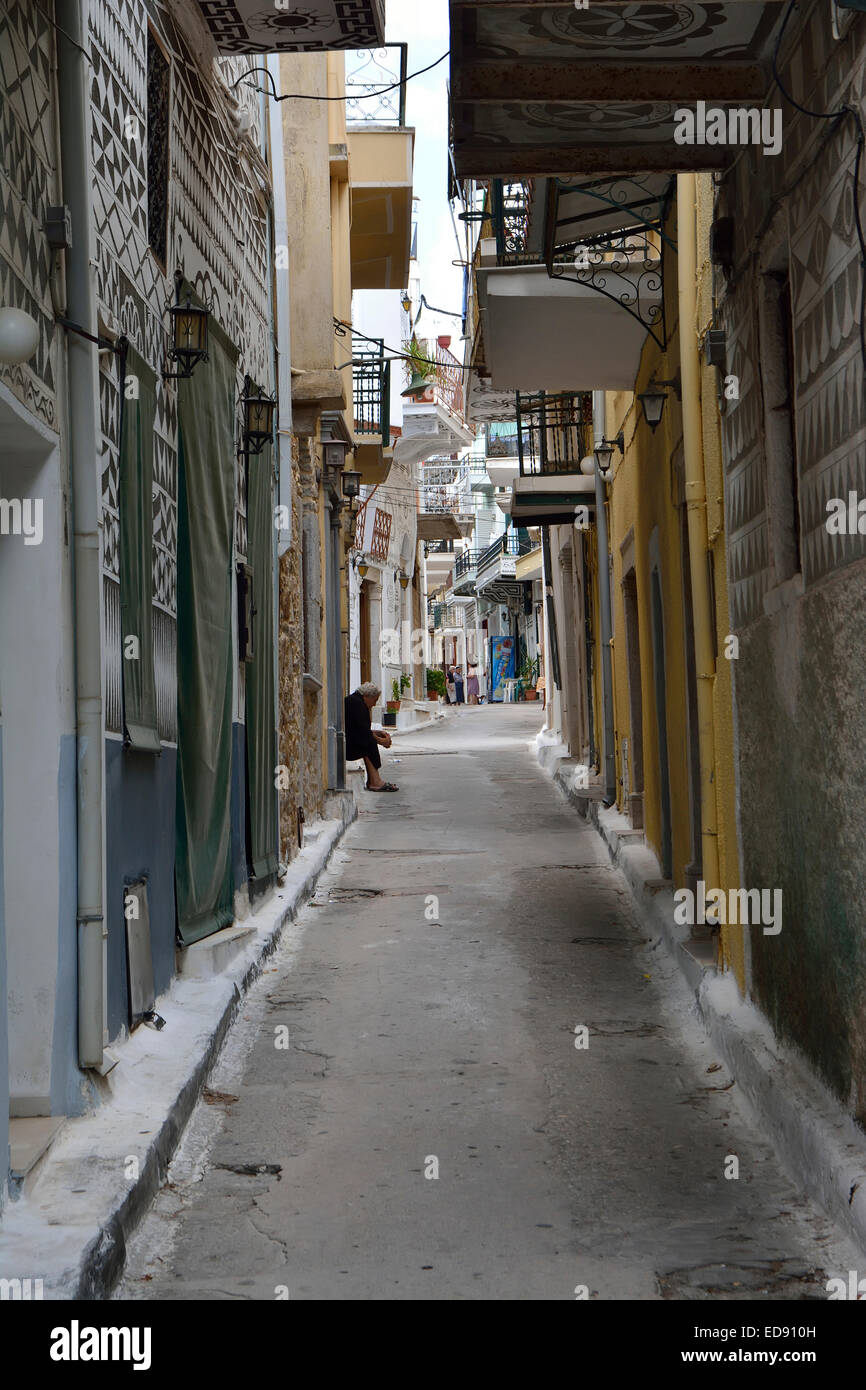 Scène de rue dans le village de Pyrgi, Chios, avec une vieille femme sur un siège Banque D'Images