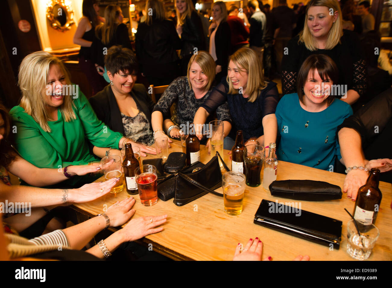 Un groupe de femmes les amis de rire et s'amuser jouant un jeu à boire dans un pub à Aberystwyth, Pays de Galles Royaume-uni le 'Black Friday', 'Black-eye vendredi' ou 'Mannonce vendredi' - le dernier vendredi avant Noël, jour où traditionnellement les gens se rendent en ville pour célébrer avec leurs collègues et camarades de travail de bureau Banque D'Images