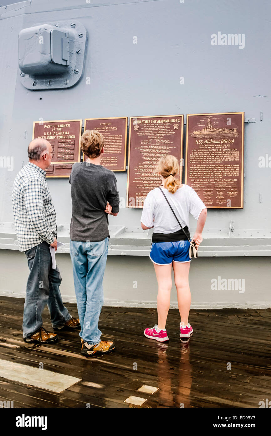 Un père avec ses enfants lire le dévouement et les plaques sur une tourelle à canon du cuirassé USS Alabama situé dans le mémorial par Banque D'Images