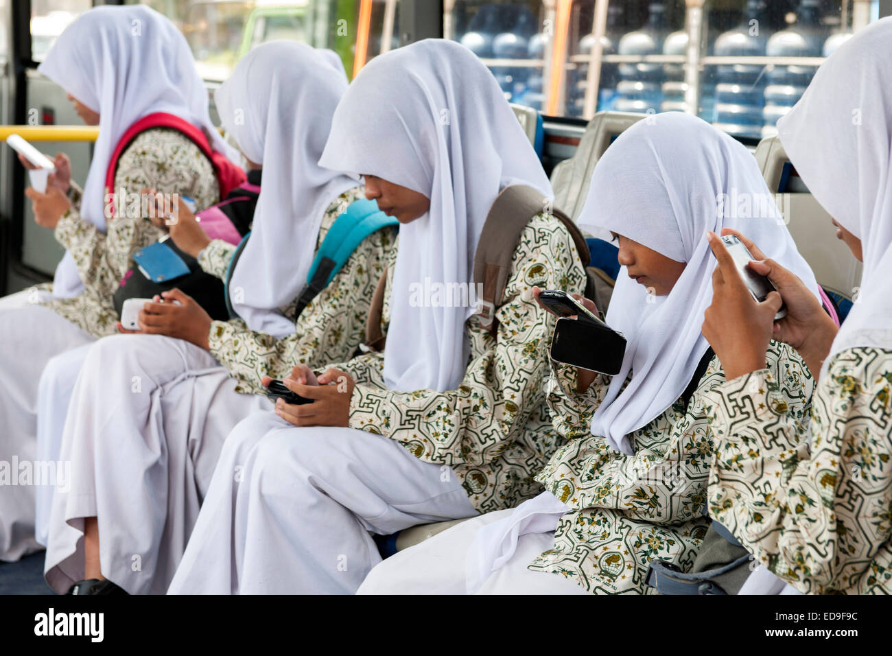 Filles de l'école de balinais avec leurs téléphones intelligents sur un bus à Bali, Indonésie. Banque D'Images