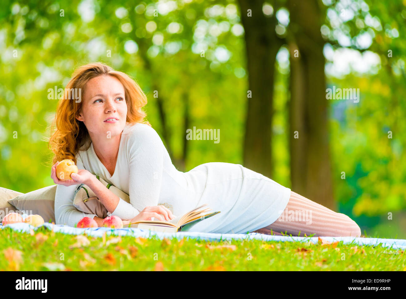 Brown-eyed girl avec une pomme dans un parc d'été Banque D'Images